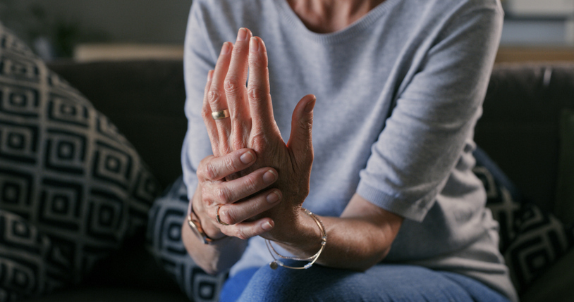 Senior lady experiencing pain in her left hand. She is using her right hand to support her left hand