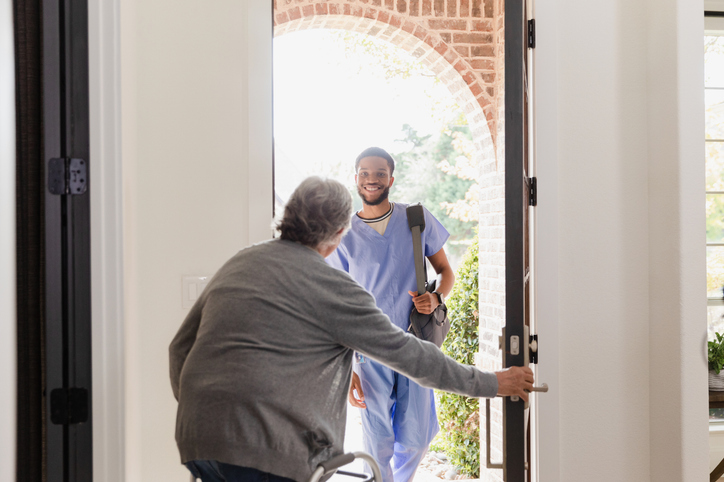 A female senior welcoming a male nurse into her home to provide respite care