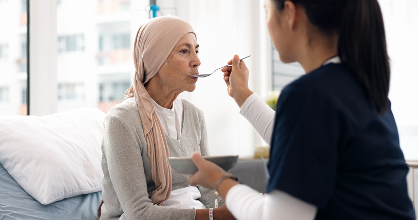 Cancer, nurse and food with old woman in hospital for help, medical and support. Healthcare, medicine and rehabilitation with senior patient and caregiver in clinic for nursing, empathy and oncology stock photo.